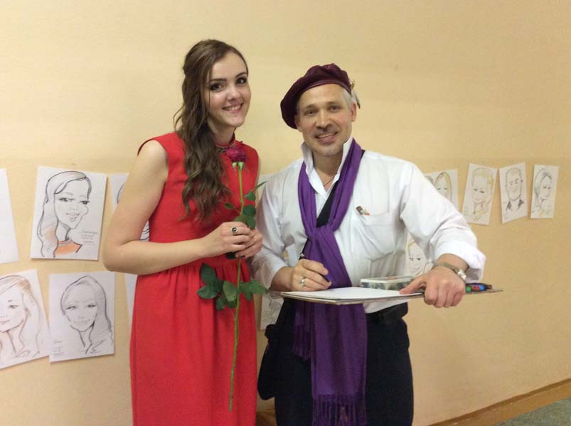  шаржист на свадьбе позирует с девушкой в красном на фоне шаржей