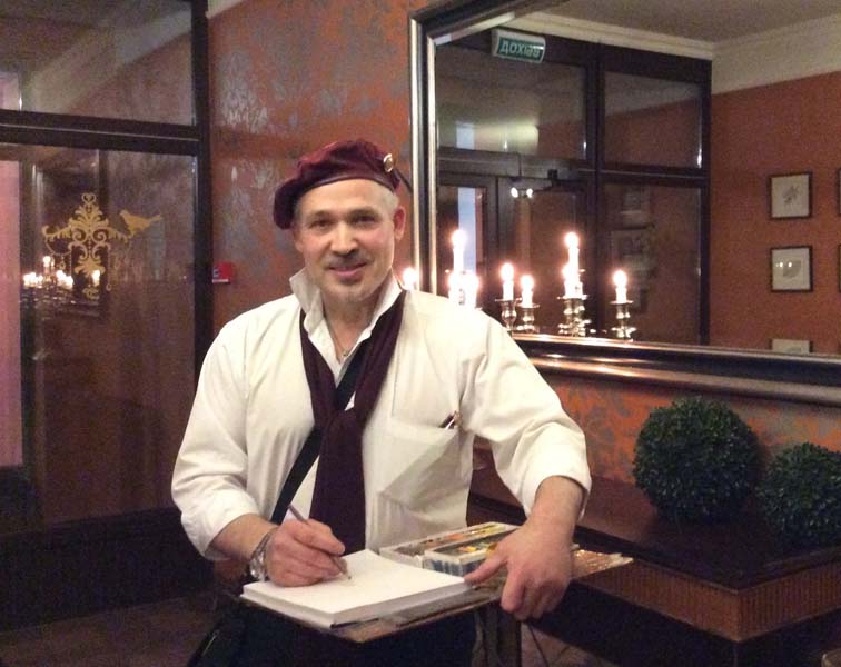  шаржист на свадьбе позирует с девушкой в красном на фоне шаржей